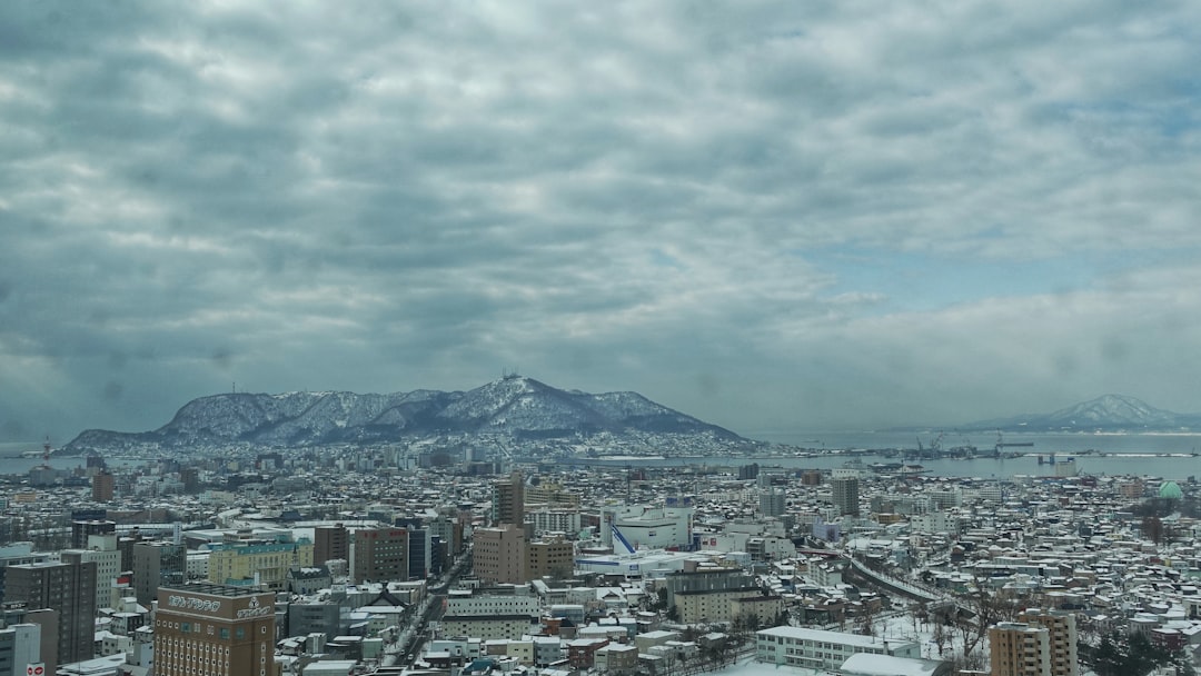 city with high rise buildings near mountain under white clouds during daytime
