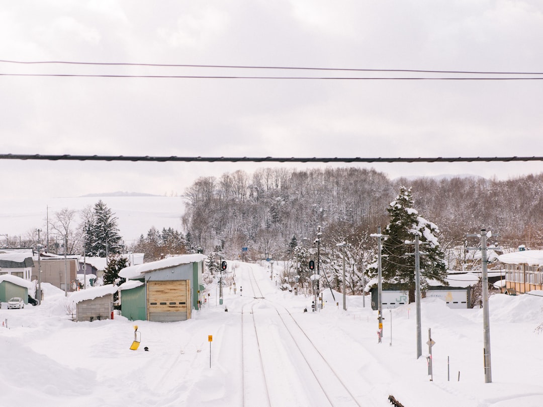 a snow covered street with a train track running through it