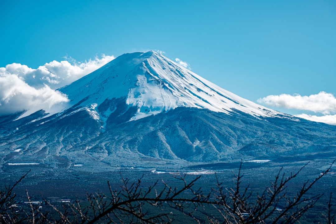 a snow covered mountain in the middle of a blue sky